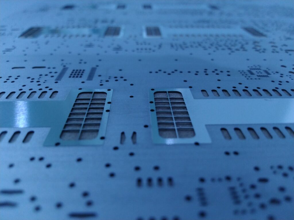 Close-up of a laser-cut stencil for SMT solder paste deposition on PCBs.