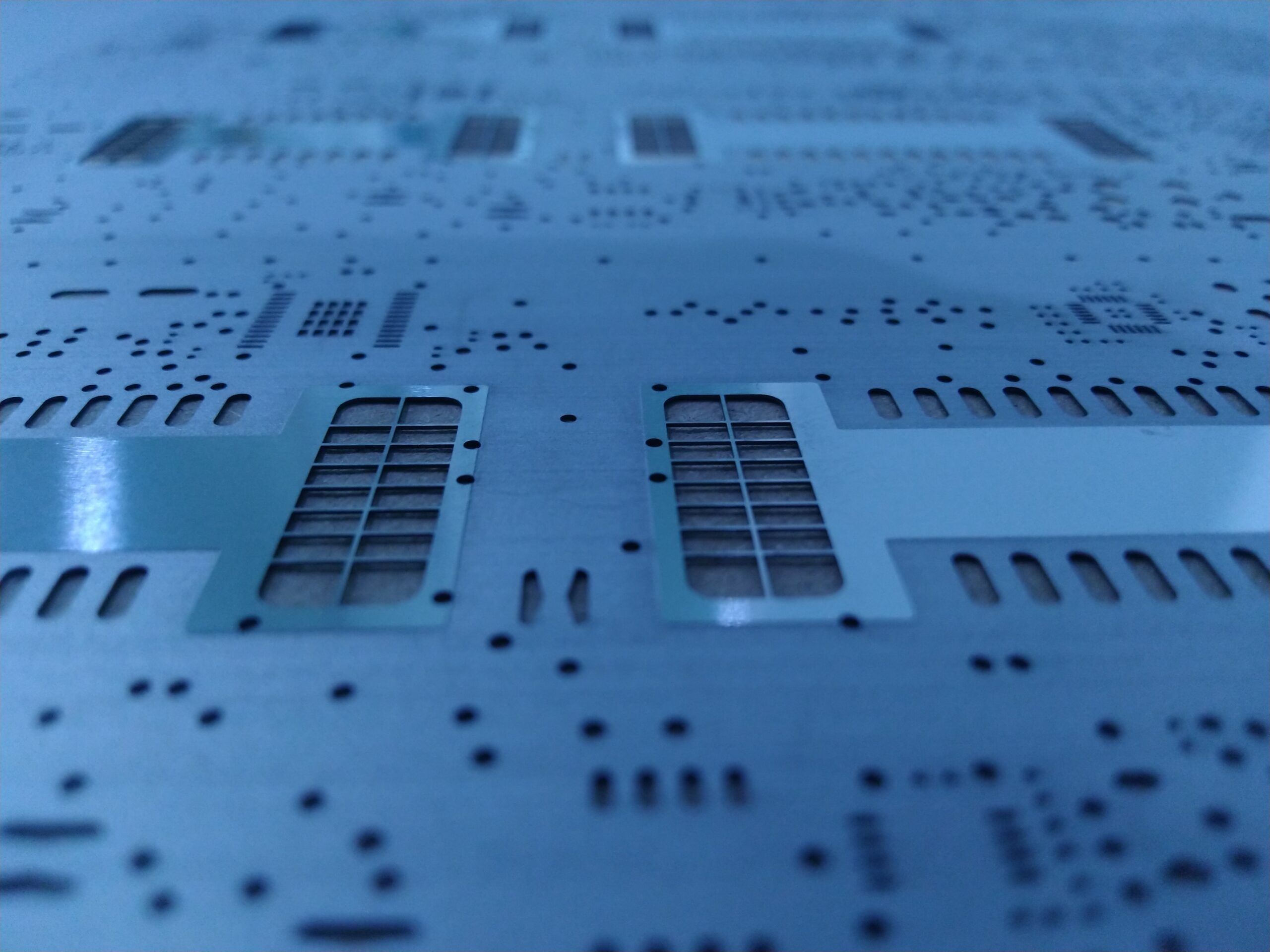 Close-up of a laser-cut stencil for SMT solder paste deposition on PCBs.
